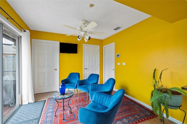 3910 77th Pl E, Sarasota, FL 34243 - living area with ceiling fan, a textured ceiling, and baseboards