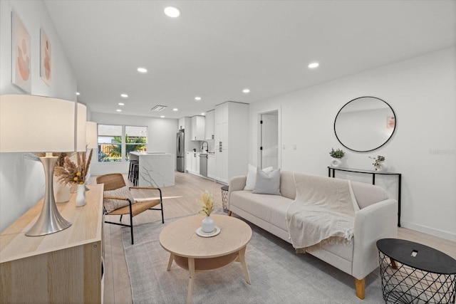 living room featuring recessed lighting, baseboards, and light wood-type flooring