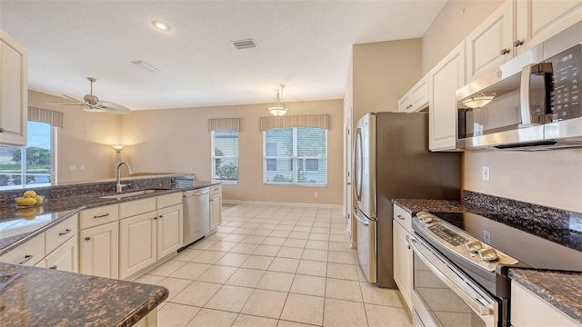 4274 Tennyson Way, Venice, FL 34293 - kitchen featuring appliances with stainless steel finishes, a sink, a ceiling fan, light tile patterned flooring, and dark stone counters
