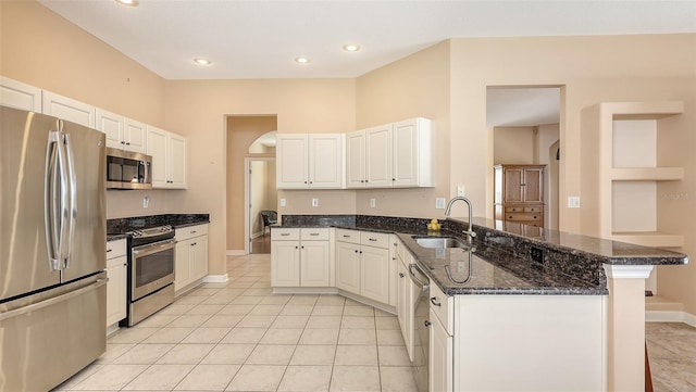 4274 Tennyson Way, Venice, FL 34293 - kitchen with stainless steel appliances, a sink, a peninsula, dark stone counters, and baseboards