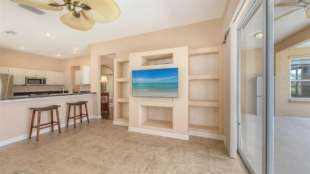 4274 Tennyson Way, Venice, FL 34293 - kitchen featuring stainless steel appliances, dark countertops, ceiling fan, built in features, and white cabinetry