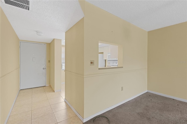 unfurnished room with a textured ceiling, baseboards, and light tile patterned floors