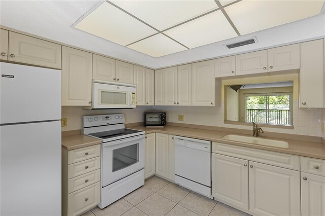 kitchen with white appliances, a sink, light tile patterned flooring, and light countertops