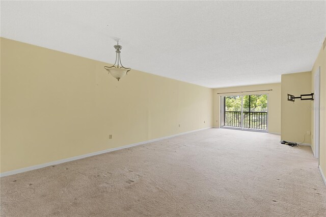 spare room featuring light carpet and baseboards