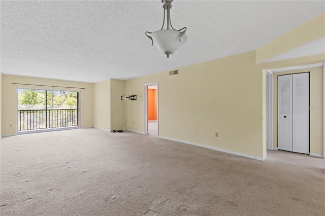 spare room with a textured ceiling, light carpet, and baseboards