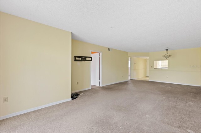 unfurnished living room with carpet, baseboards, and a textured ceiling