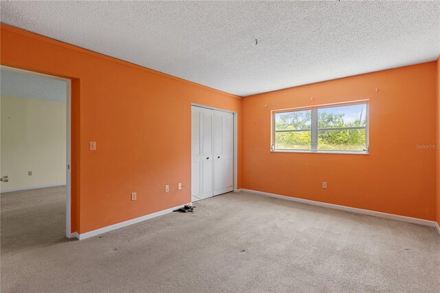 unfurnished bedroom with carpet flooring, a textured ceiling, a closet, and baseboards