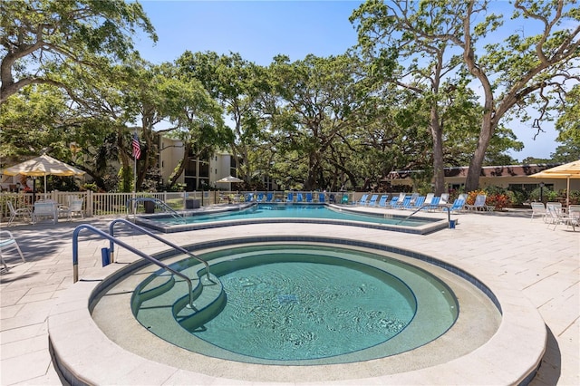 community pool featuring a hot tub, fence, and a patio area