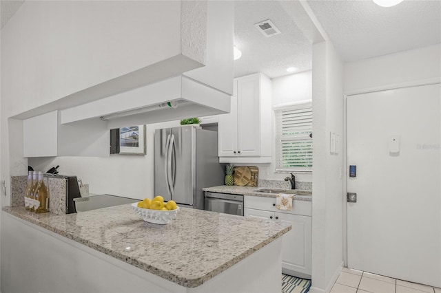 5681 Midnight Pass Rd Unit 104, Sarasota, FL 34242 - kitchen featuring appliances with stainless steel finishes, a sink, white cabinets, a textured ceiling, and a peninsula