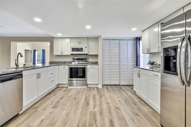 7308 Maryland Ave, Hudson, FL 34667 - kitchen featuring stainless steel appliances, a sink, light wood-style floors, white cabinetry, and light stone countertops