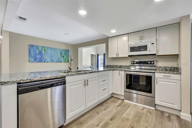 7308 Maryland Ave, Hudson, FL 34667 - kitchen with stainless steel appliances, a sink, light wood-style flooring, light stone counters, and white cabinets