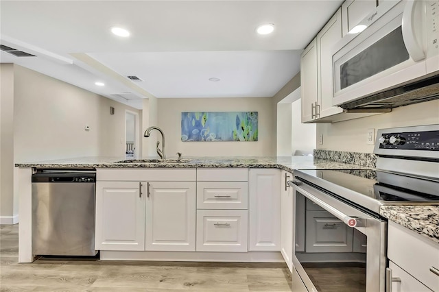 7308 Maryland Ave, Hudson, FL 34667 - kitchen featuring stainless steel appliances, a sink, light stone counters, white cabinets, and recessed lighting