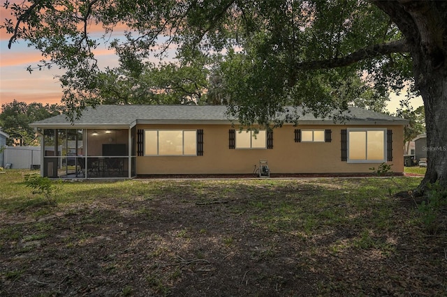 4468 Maraldo Ave, North Port, FL 34287 - back of property at dusk with a sunroom, stucco siding, and a yard