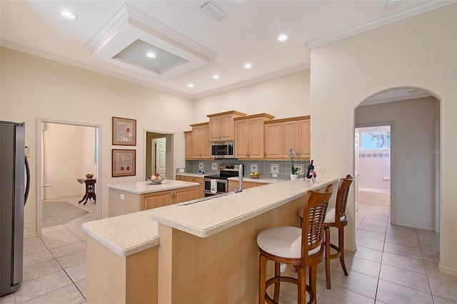 766 Shadow Bay Way, Osprey, FL 34229 - kitchen with stainless steel appliances, arched walkways, light tile patterned flooring, backsplash, and a high ceiling