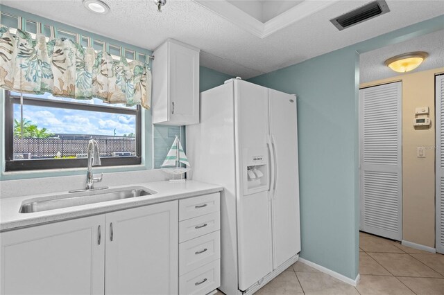 1001 Benjamin Franklin Dr Unit 106, Sarasota, FL 34236 - kitchen with a sink, white refrigerator with ice dispenser, light tile patterned floors, white cabinets, and light countertops