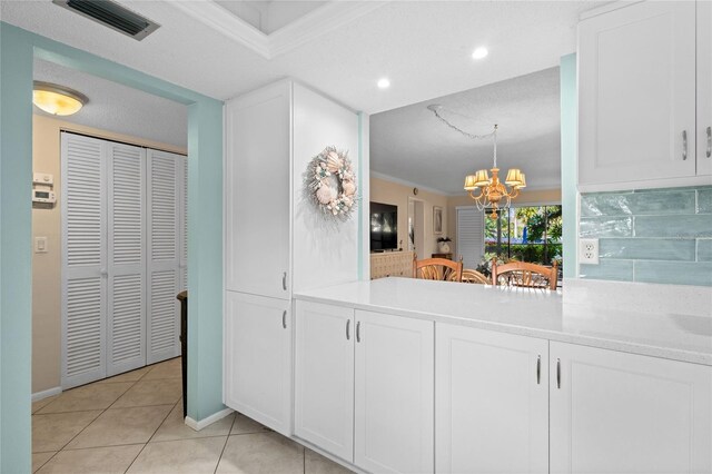1001 Benjamin Franklin Dr Unit 106, Sarasota, FL 34236 - kitchen featuring a chandelier, ornamental molding, white cabinets, light tile patterned flooring, and light countertops
