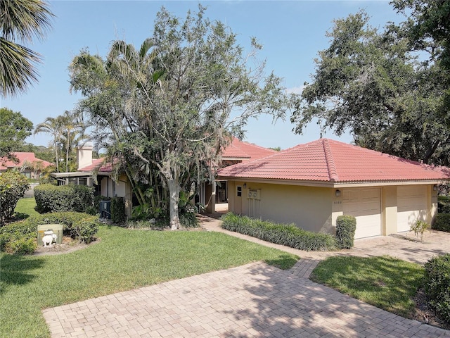 5039 Kestral Park Dr Unit 67, Sarasota, FL 34231 - view of front of house with stucco siding, a front yard, a tiled roof, an attached garage, and driveway