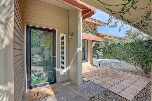 5039 Kestral Park Dr Unit 67, Sarasota, FL 34231 - view of exterior entry with a patio, stucco siding, and outdoor dining space