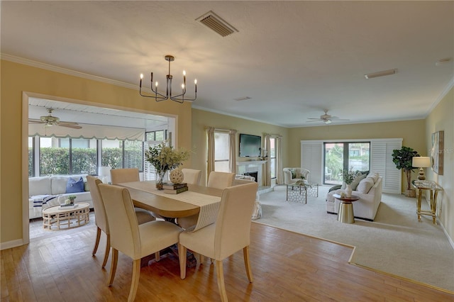 5039 Kestral Park Dr Unit 67, Sarasota, FL 34231 - dining room featuring ornamental molding, a ceiling fan, a fireplace, wood finished floors, and a chandelier