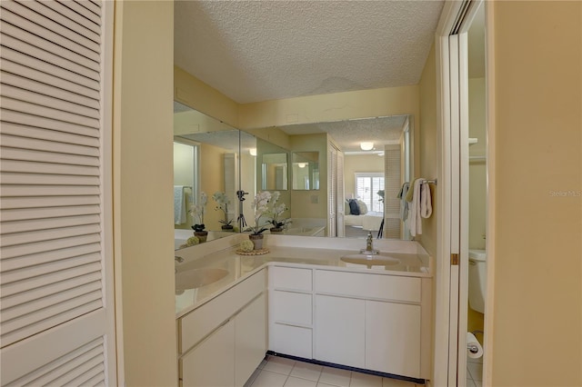 5039 Kestral Park Dr Unit 67, Sarasota, FL 34231 - bathroom with a textured ceiling, tile patterned floors, double vanity, and toilet