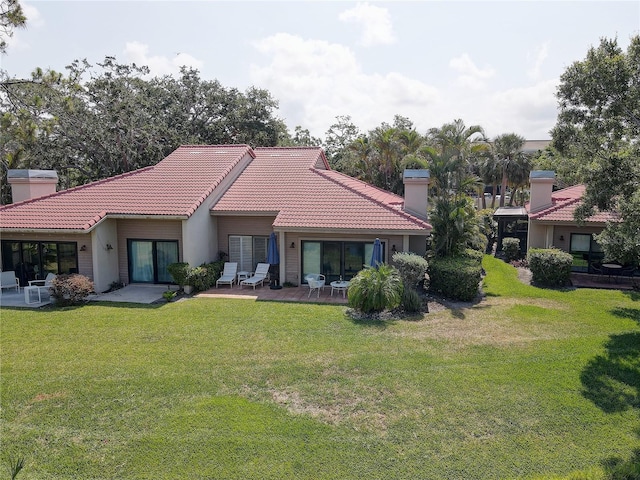 5039 Kestral Park Dr Unit 67, Sarasota, FL 34231 - rear view of property featuring a chimney, a tiled roof, and a lawn