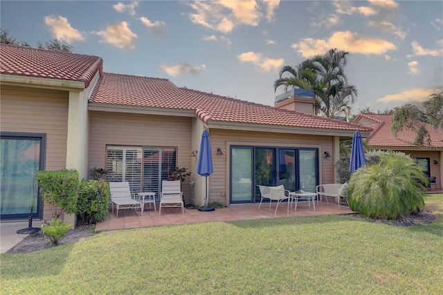 5039 Kestral Park Dr Unit 67, Sarasota, FL 34231 - rear view of property with a patio, a lawn, and a tile roof