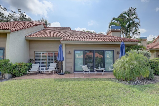 5039 Kestral Park Dr Unit 67, Sarasota, FL 34231 - back of property featuring a patio area, a yard, a tiled roof, and a chimney