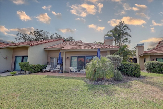 5039 Kestral Park Dr Unit 67, Sarasota, FL 34231 - rear view of property with a patio area, a yard, a tile roof, and stucco siding