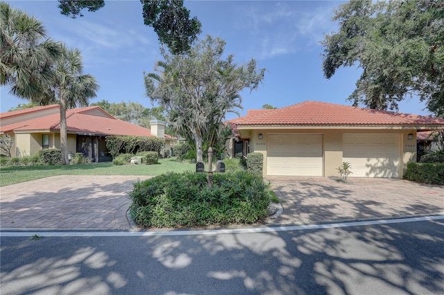 5039 Kestral Park Dr Unit 67, Sarasota, FL 34231 - view of front facade featuring stucco siding, a tiled roof, a garage, and decorative driveway