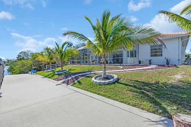3620 Como St, Port Charlotte, FL 33948 - view of front of house featuring a front yard, stucco siding, glass enclosure, and a tiled roof