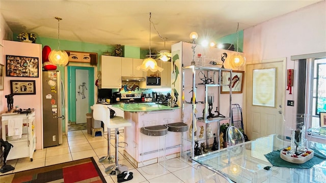 409 Bryn Mawr Is, Bradenton, FL 34207 - kitchen featuring appliances with stainless steel finishes, under cabinet range hood, light tile patterned floors, a kitchen breakfast bar, and hanging light fixtures