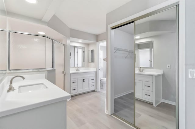 251 Broadmoor Ln, Rotonda West, FL 33947 - full bathroom with two vanities, wood finished floors, baseboards, toilet, and recessed lighting