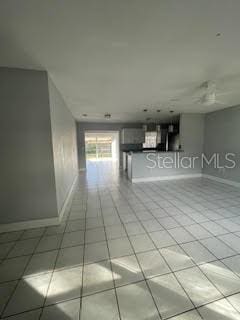 empty room with baseboards and light tile patterned floors