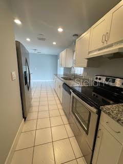 kitchen with appliances with stainless steel finishes, a sink, under cabinet range hood, recessed lighting, and light tile patterned flooring