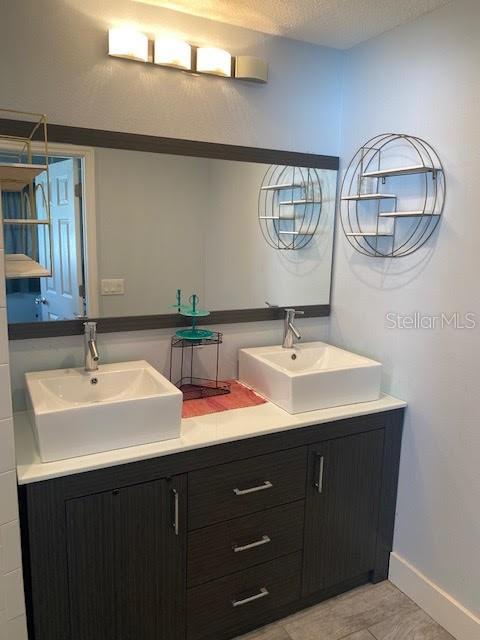 bathroom with baseboards and double vanity