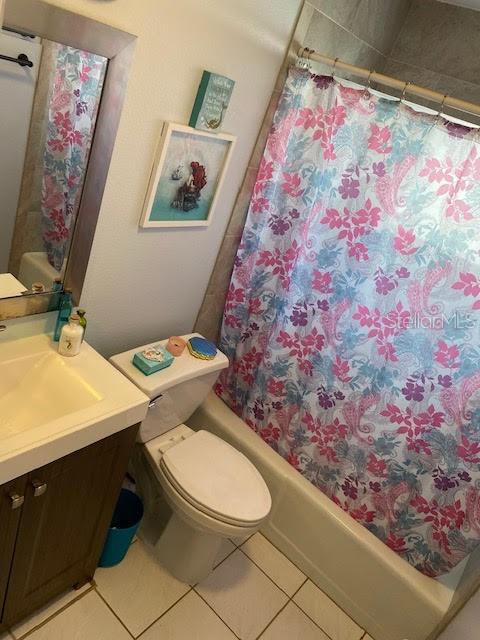 full bathroom with tile patterned flooring, toilet, vanity, and shower / bathtub combination with curtain