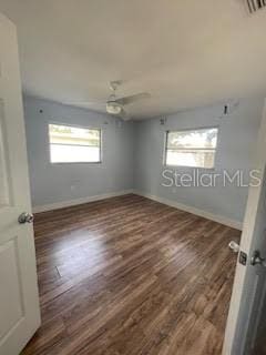 unfurnished room featuring plenty of natural light, wood finished floors, and baseboards