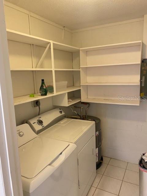 laundry room with washer and dryer, a textured ceiling, and light tile patterned floors