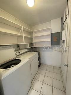 washroom featuring washing machine and dryer, electric panel, and light tile patterned floors