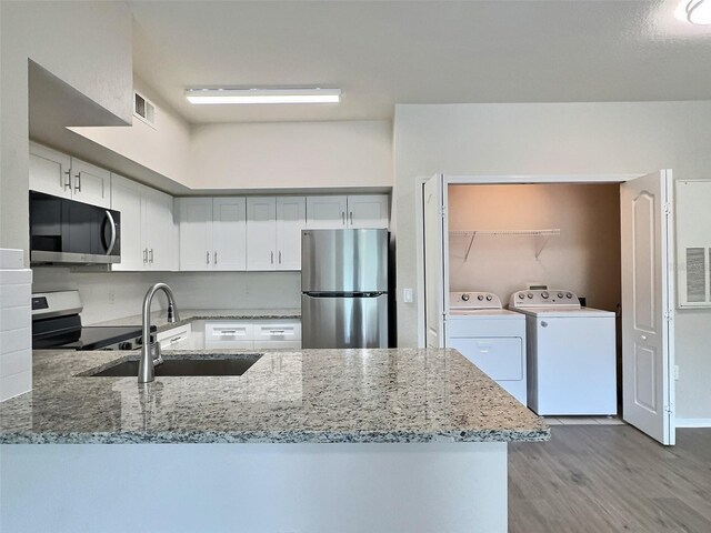 4142 Central Sarasota Pkwy Unit 1423, Sarasota, FL 34238 - kitchen featuring appliances with stainless steel finishes, washing machine and dryer, a sink, light stone countertops, and light wood-style floors