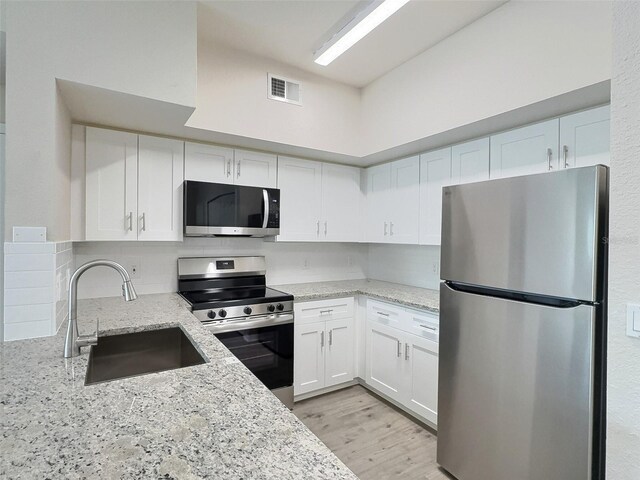 4142 Central Sarasota Pkwy Unit 1423, Sarasota, FL 34238 - kitchen featuring appliances with stainless steel finishes, a sink, white cabinetry, and light stone counters