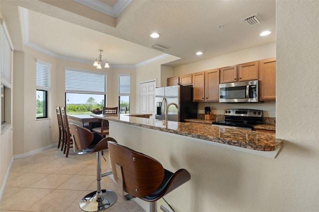 7005 River Hammock Dr Unit 203, Bradenton, FL 34212 - kitchen featuring stainless steel appliances, a chandelier, a kitchen bar, ornamental molding, and dark stone counters