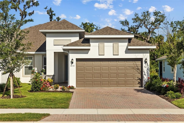 5816 Mezzana Run, Palmetto, FL 34221 - view of front facade featuring stucco siding, an attached garage, decorative driveway, a front yard, and roof with shingles