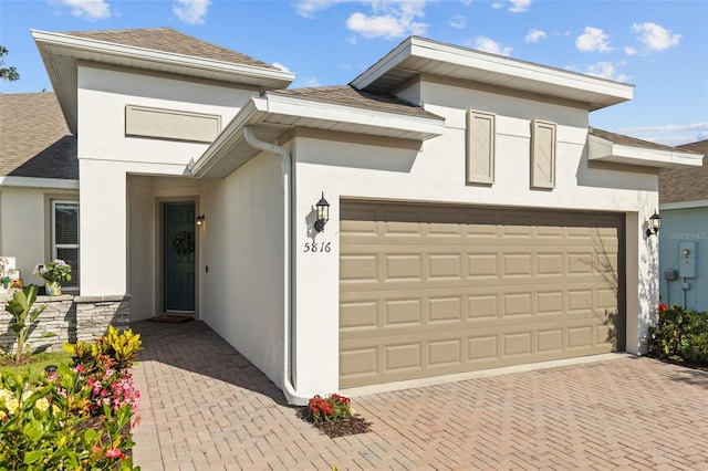 5816 Mezzana Run, Palmetto, FL 34221 - view of front facade featuring stucco siding, an attached garage, decorative driveway, and a shingled roof