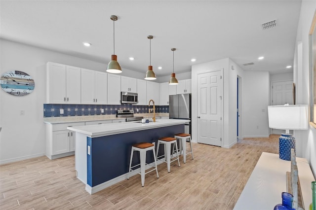 5816 Mezzana Run, Palmetto, FL 34221 - kitchen with stainless steel appliances, light wood-type flooring, decorative backsplash, white cabinets, and recessed lighting