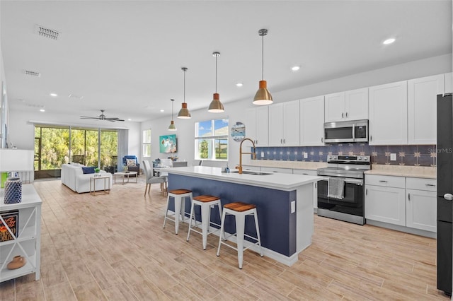 5816 Mezzana Run, Palmetto, FL 34221 - kitchen featuring appliances with stainless steel finishes, a sink, open floor plan, light countertops, and decorative backsplash