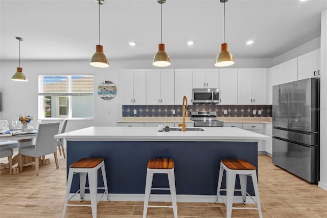 5816 Mezzana Run, Palmetto, FL 34221 - kitchen with appliances with stainless steel finishes, a sink, light countertops, decorative backsplash, and a kitchen breakfast bar