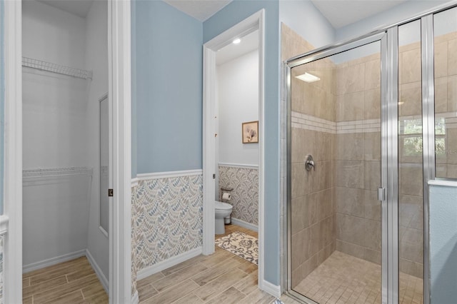 5816 Mezzana Run, Palmetto, FL 34221 - bathroom featuring a stall shower, a wainscoted wall, wood finish floors, toilet, and a walk in closet