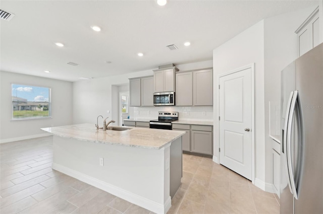 kitchen featuring stainless steel appliances, gray cabinets, a sink, a kitchen island with sink, and recessed lighting