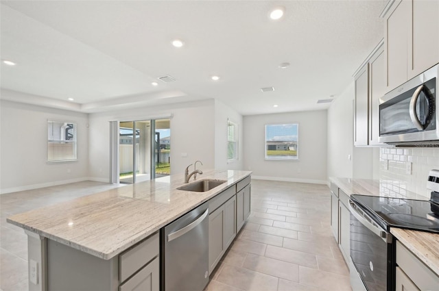 kitchen featuring a sink, stainless steel appliances, gray cabinetry, open floor plan, and recessed lighting